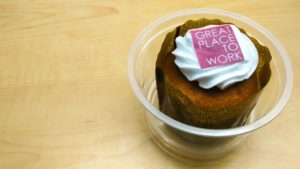 Picture of a small cake with a decoration on the top saying "Great Place To Work". 