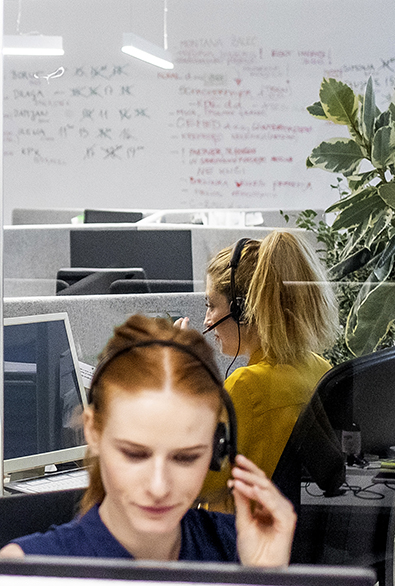 Visage de deux femmes, une au premier plan, l'autre plus loin avec des micros casques (contexte de travail). 