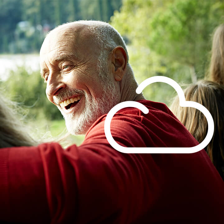 Homme âgé sourit entouré d'autres personnes (ambiance familiale). En surimpression un pictogramme nuage blanc.