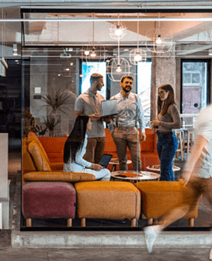 4 people talking in a glassed-in office.