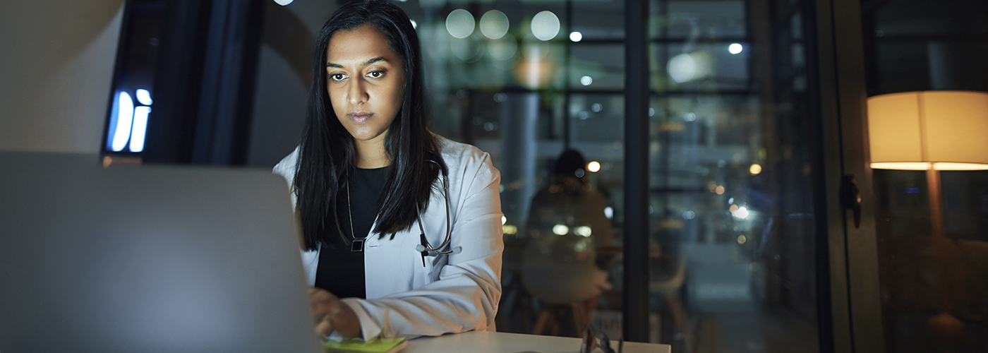 A young doctor behind a computer (nocturnal atmosphere).