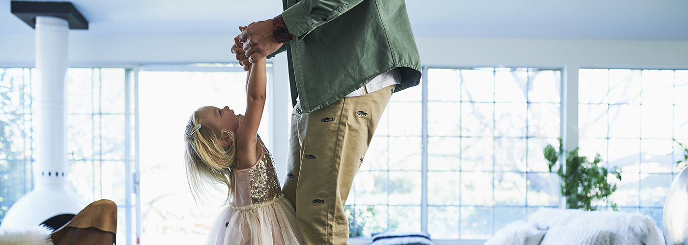 Little girl playing with her father in a living room. 