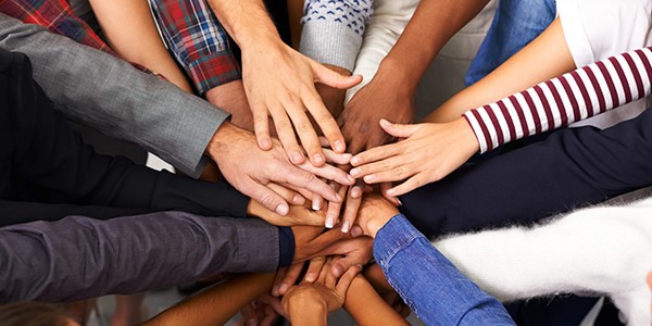 About twenty multi-ethnic hands on top of each other.