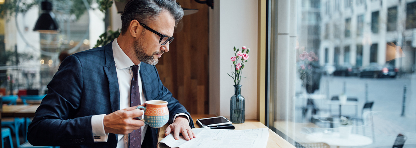 Homme d'affaires lisant le journal en buvant un café dans un restaurant. 